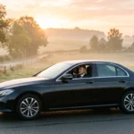Mercedes Classe E noire avec chauffeur professionnel sur une route du Brabant wallon au lever du jour